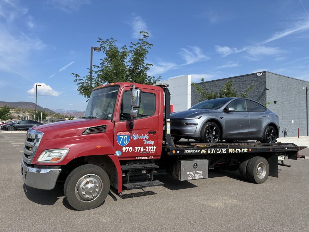 Affordable Towing red flatbed carrying an electric SUV in Eagle County, Colorado